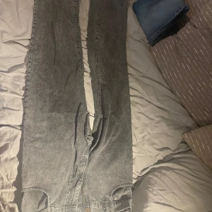 Gråa jeans med Loose fit - Säljer ett par gråa jeans med hög midja och raka ben. Jeansen har klassisk femficksdesign och dragkedja framtill. Perfekta för dig som gillar en avslappnad och tidlös look. Passar till allt och är superenkla att styla. 32 W 32 L