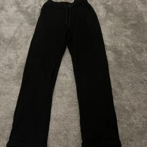 Svarta mjukisbyxor från Kappahl - Svarta mjukisbyxor från Kappahl i storlek 134. Byxorna har normal passform, resår i midjan med snörning och knapp framtill. De har raka ben och är tillverkade i mjukt bomullsmaterial, perfekta för chill dagar eller häng med kompisar.