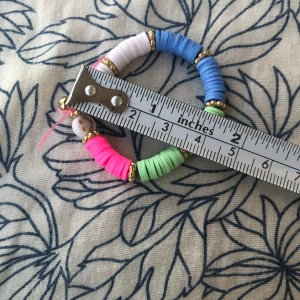 Jätte fina han gjorda armband. Både killar och tjejer. - Säljer ett coolt armband med platta pärlor i blått, vitt, rosa och grönt, dekorerat med små guldfärgade pärlor och en vit smiley-pärla. Perfekt accessoar för dig som gillar färg och lekfull stil. Stretchig och bekväm att bära.