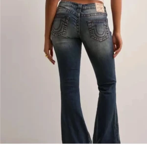 True Religion blå bootcut jeans w28 (fri frakt kolla min profil!!!) - Säljer ett par blå low waist jeans från True Religion med bootcut passform. Jeansen har röda kontrastsömmar. Dom är sydda vid midjan men det går att sprätta bort.  Skriv om ni vill att jag ska ta bort det jag har sytt runt midjan!!! Storlek 28 vilket ungefär motsvaras storlek S/36. Nya pris är 1 299