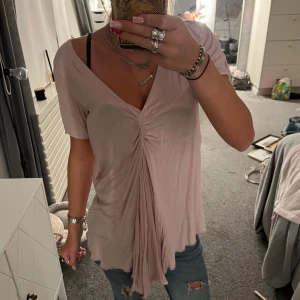 Ljusrosa omlottopp  - Supersöt ljusrosa topp från Wera med v-ringning och snygg omlottdetalj framtill. Tunt och flowy material som känns luftigt, perfekt till jeans eller kjol. Kortärmad och med lätt rynk framtill för en chill men ändå trendig look.