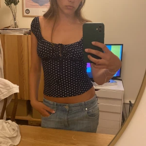 Mörkblå prickig topp med snörning - Supersöt mörkblå topp från Jane norman med vita prickar, söt snörning framtill och puffade axelband. Så himla fin att ha till fest eller middagar!