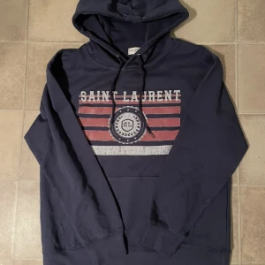 Saint Laurent Hoodie - Tjenare, säljer en eftertraktad Saint Laurent Hoodie som är i storlek M. Tröjan är i superbra skick och har du frågor är de bara höra av sig✌️(kan gå ner i pris vid snabb affär)