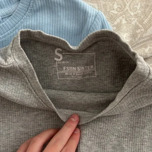 2 ribbade toppar från FSBN Sister S - Två ribbade toppar från FSBN Sister i storlek S. En är ljusblå och den andra är ljusgrå.