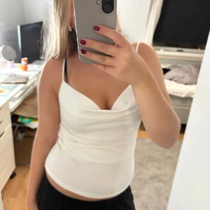 Vit festlig topp - Säljer en vit topp med smala axelband och sommar perfekt för fest tillfällen. Toppen är figurnära och har en enkel, fräsch look som passar perfekt till jeans eller kjol. Aldrig använd och köpt på hm i Italien