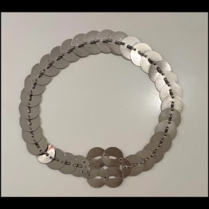 Silvrigt bälte med runda plattor - Unikt bälte i silverfärgad metall med stora, runda plattor som är länkade ihop. Ca 75-76cm. Hämtas i Hägersten. 