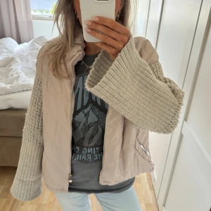 Beige pufferjacka med stickade ärmar - Säljer en beige pufferjacka med stickade ärmar i ljusgrått. Perfekt för dig som vill ha en unik och trendig look. Så snygg i vår och sommar!❣️