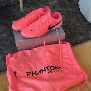 Nike Phantom GX ll Elite Fg fotbollsskor  - Köptes för 3250. Endast använd 2 gånger då de inte passade, som nya!! Säljer ett par Nike Phantom GX ll Elite FG fotbollsskor i en riktigt snygg rosa färg med svarta detaljer. Pris kan diskuteras!!