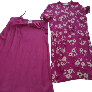 Rosa blommig klänning från MAX&Co. - Säljer en rosa långklänning från MAX&Co. med vita blommor och korta ärmar. Klänningen är tillverkad i 100% viskos och har volangdetaljer framtill. Perfekt för dig som gillar färg och mönster!