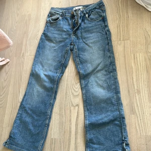 Blå jeans från Zara med raka ben - Klassiska blå jeans från Zara med raka ben och normal passform. Byxorna har fem fickor, dragkedja och knapp framtill. Perfekta för en avslappnad stil och lätta att matcha med olika toppar.