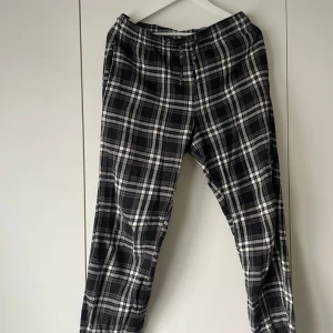 Svarta och vita rutiga mjukisbyxor från 157 - Mysiga mjukisbyxor från 157 i svartvitt rutigt mönster. Byxorna har resår och snörning i midjan för extra komfort. Perfekta för chill dagar hemma eller när du vill ha det extra bekvämt.