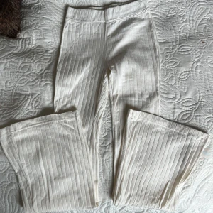 Creme vitt set  - Säljer ett cremevitt ribbat set med en cropped huvtröja, linne med v-ringning och utsvängda byxor.  Settet är från H&M och har knappt använts. Allt är i samma färg, det är bara ljuset som får det att se lite olika ut. 