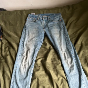 Ljusblå Levi's jeansbyxor - Säljer ett par klassiska ljusblå jeans från Levi's med fem fickor och orange sömmar. Byxorna har normal passform och raka ben. Perfekta för dig som gillar en tidlös denimlook.