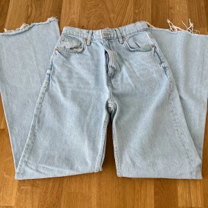 Ljusblå wide jeans med råa kanter - Säljer ljusblå jeans med breda ben från fb sister. Klassisk femficksmodell med hög midja och raka bakfickor. Perfekta för en avslappnad och trendig look.