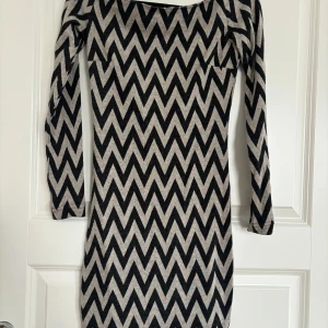 Svart och beige mönstrad klänning från Lefon - Säljer en långärmad klänning från Lefon i storlek 38 med svart och beige zigzag-mönster. Klänningen har en kroppsnära passform och är tillverkad i ett mjukt, stretchigt material. Perfekt för dig som gillar grafiska mönster!