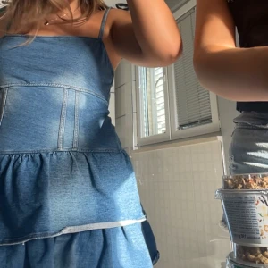 Jeansklänning med volanger och smala axelband - Säljer en blå jeansklänning med smala axelband och volangkjol. Klänningen har dragkedja i ryggen och är sydd i flera lager för en snygg volangeffekt. Perfekt för dig som gillar denim och vill ha en cool och avslappnad stil.