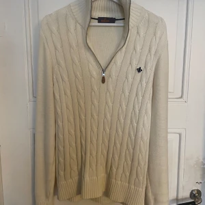 Beige stickad tröja med dragkedja från Morris - Säljer en beige stickad tröja från Morris med kabelstickat mönster och halv dragkedja framtill. Tröjan har hög krage och funkar perfekt till sommar kvällar.☀️Mycket fint skick!
