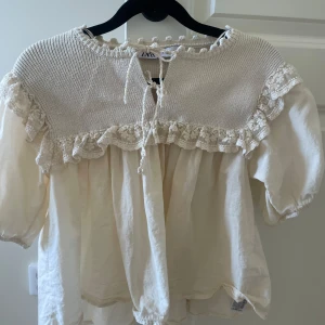 Beige blus med volanger från Zara, strl S - Beige blus från Zara i storlek S. Stilren modell med volangdetaljer framtill och ett lätt, bekvämt tyg – perfekt både till vardags och till festligare tillfällen. Använd ett fåtal gånger och i mycket fint skick, utan fläckar eller skador. Modellen säljs inte längre i butik. Hör av dig vid frågor!