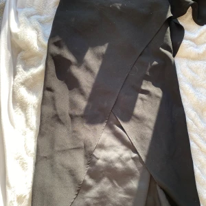 Svart omlottkjol från & Other Stories - Säljer en svart lång omlottkjol från & Other Stories, Paris Atelier. Kjolen har en elegant omlottdesign och är tillverkad i ett mjukt, slätt material som ger ett stilrent intryck. Perfekt för dig som gillar klassiska och tidlösa plagg. Har några små prickar se defekt på sista bilden💕