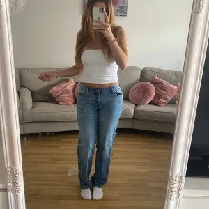 Blå jeansbyxor från Bubbleroom - Säljer ett par klassiska blå jeansbyxor från Bubbleroom med normal passform och raka ben. Byxorna har fyra fickor, bälteshällor och stängs med dragkedja och knapp. Perfekta till många olika stilar.