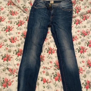 Blå jeansbyxor från lee  - Säljer ett par klassiska blå jeansbyxor från lee med fem fickor och dragkedja. Jeansen har en normal passform och raka ben, perfekt för en avslappnad stil. Snygga slitningar framtill och diskreta sömmar baktill.