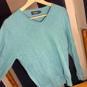 Turkos bomullströja från Dressmann - Snygg turkos långärmad tröja från Dressmann i mjuk supima-bomull. Tröjan har v-ringad hals och en clean look utan mönster eller detaljer, perfekt för dig som gillar enkel och stilren stil. Aldrig använd!