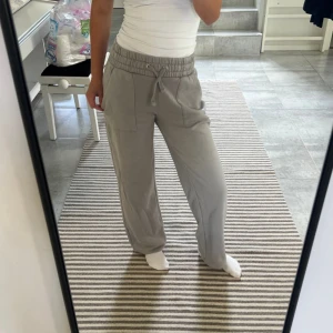 Grå mjukisbyxor med snörning - Säljer ett par grå mjukisbyxor med bred resår i midjan och snörning framtill. Byxorna har raka ben, stora fickor fram och en bakficka. Sköna och loose fit, perfekta för chill dagar.