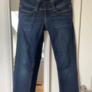 Lågmidjade jeans från Pepe Jeans - Lågmidjade mörkblå jeans från Pepe Jeans. Jeansen har raka ben och normal passform, perfekt till vardagslooken. Dragkedjan är sönder men går att byta. 