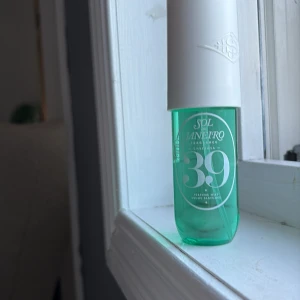 Sol de Janeiro Cheirosa 39 Parfym - Fräsch parfymmist från Sol de Janeiro, Cheirosa 39. Flaskan är genomskinlig med turkosgrönt innehåll och har en stilren vit kork. Perfekt sprayflaska i plast, 90 ml. Doften är tropisk och modern, med en snygg och ungdomlig design.