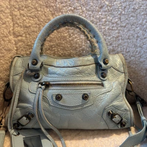 Ljusblå Balenciaga handväska  - Superfin ljusblå handväska från Balenciaga i äkta skinn🩷 en plupp har tyvärr gått av, syns dock knappt men behöver ju nämna det! pris kan diskuteras💕köptes för 7000 på collecterscage