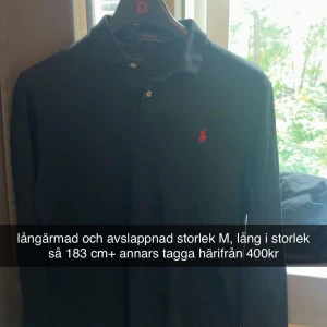 Svart långärmad pikétröja Polo Ralph Lauren - Svart långärmad pikétröja från Polo Ralph Lauren i storlek M. Klassisk krage med knappar och röd broderad logga på bröstet. Perfekt för dig som är lite längre, avslappnad passform och stilren look.