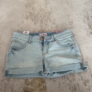 Ljusblå jeansshorts från Vingino - Snygga ljusblå jeansshorts från Vingino med klassisk femficksdesign och uppvikta benslut. Shortsen har en normal passform. 💗