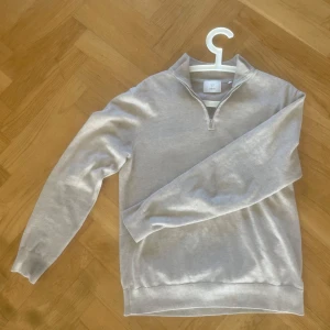 Beige half zip-tröja från Bläck - Säljer stilren beige tröja från Bläck med half zip-dragkedja och hög krage. Den är i bra skick skulle säga 8-10.