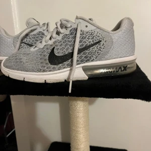 Nike Air Max Sequent 2 grå sneakers - Nike Air Max Sequent 2 sneakers i grått och vitt med svart swoosh. Ovandel i stickad mesh för bra andningsförmåga och synlig Air Max-dämpning i hälen. Klassisk snörning och platt sula. Perfekta för dig som gillar sportig och clean stil. Är i NYSKICK! Nypris 1590kr