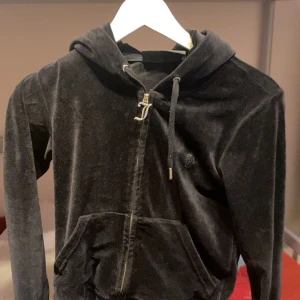 Svart velour hoodie Juicy Couture XS - Säljer en svart hoodie från Juicy Couture i mjuk velour med dragkedja och huva. Tröjan har långa ärmar, snörning i huvan och en stor ficka framtill. Har använt en gång är i bra skick