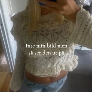 Vit stickad croppad tröja med volang - Superfin vit stickad tröja med volangdetaljer och hålmönster. Croppad modell med långa ärmar och rund hals.Passar till både jeans och kjol, och är riktigt mysig på hösten och våren.