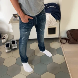 Blå slim jeans med slitningar - Säljer ett par riktigt feta jeans från jack and Jones med slitningar, skriv om du har några frågor eller funderingar!!!