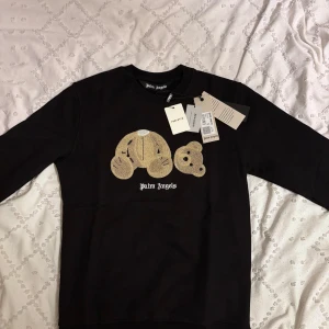 Palm Angels sweatshirt - Svart sweatshirt från Palm Angels med ikoniskt nalletryck framtill och broderad logga. Tröjan har rund hals, långa ärmar och är gjord i 100% bomull. Perfekt för dig som gillar streetwear och vill sticka ut med en unik detalj.