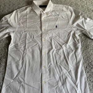 Polo Ralph Lauren vit skjorta - Snygg polo Ralph Lauren vit skjorta i storlek M. Helt ny och bara använt vid test, på bilderna har jag inte strukit skjortan så den ser lite sliten ut.
