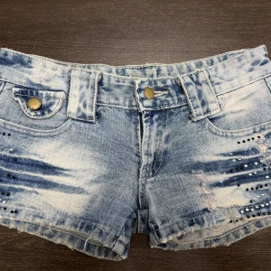 Jeansshorts  - Snygga ljusblå jeansshorts med slitna detaljer och paljetter, jättefina nu till sommaren. Midjemåttet rakt över är 35 cm. Obs! Jag är på semester och kan därmed skicka tidigast 28/6