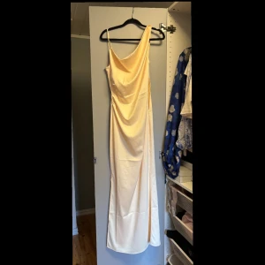 Adoore klänning intressekoll - Supersnygg långklänning från Adoore. I Almeria maxiklänning i vanilla yellow. Klänningen är axelbandslös på ena sidan och har en draperad diagonal urringning, rynkade detaljer i midjan och en dold dragkedja i sidan. Klänningen är i maxilängd och har en slits längs den nedre sidosömmen. Endast använd 1 gång. Klänningen är slutsåld på hemsidan. Perfekt för bal, bröllop eller andra sommarfester. Det är intressekoll för att kolla intresset och eventuellt pris💖kan skicka fler bilder vid intresse.