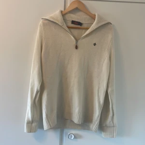 Vit stickad half zip från Morris - Snygg Vit stickad tröja från Morris med ribbad krage och muddar. Tröjan har half zip-dragkedja och en broderad logga på bröstet. Perfekt för lager-på-lager och chillare dagar. Nypris 2499.