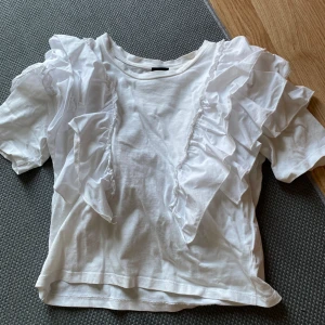Vit Gina blus - Säljer min fina gina blus med volanger i storlek XS💞🙌🏼 blusen har en liten fläck vid halsen men absolut inget stort som märks eller som sitter fast i tvätten. Skriv för fler bilder eller frågor!