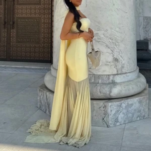 Ljusgul långklänning med släp - Superfin ljusgul långklänning med figurnära passform och långt släp. Klänningen är axelbandslös och har en snygg långt hängande sjal. Drömmig klänning