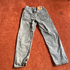 Grå Levi's loose taper jeans 12A - Grå jeans från Levi's i loose taper-modell med klassiska fem fickor och skön passform. Jeansen har en avslappnad look och är tillverkade i mjukt denimtyg. Perfekta för dig som gillar en lite mer loose och trendig stil.(dom är inte tvättade eller strykta på bilden)