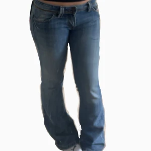 Blå bootcut jeans med broderi från Diesel - Snygga blå jeans från Diesel med bootcut passform och låg midja. Jeansen har coolt broderi som liknar drakar. De är i storlek 31 och är lite långa på mig som är 169cm. Midjemåttet är 43x2. Men de känns lite mindre för att de sitter ganska lågmidjat.