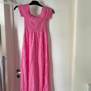 Rosa prickig maxiklänning Amisu - Söt rosa långklänning från Amusu med vita prickar, smockad överdel och korta ärmar. Perfekt för sommarens alla tillfällen när du vill känna dig extra fin. Aldrig använd, prislappen på.