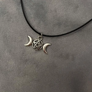 Snygg choker pentagram triple moon silver imitation  - Ett pentagram med två månskäror. Trädd  på en kortare svart tråd som är justerbar 35-40 cm. Berlocken är ca 2 x 0,8 cm. 