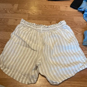 Randiga linneshorts från Cubus - Snygga randiga shorts från Cubus i beige och vitt. De är tillverkade i 100% linne, har elastisk midja och avslappnad passform. Perfekta för varma dagar när du vill ha en chill och fräsch look.