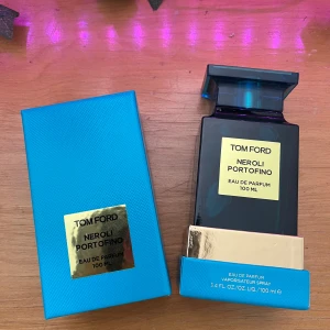 Tom Ford Neroli Portofino 100ml EdP - Tom Ford Neroli Portofino Eau de Parfum 100 ml i en lyxig, fyrkantig blå glasflaska med gulddetaljer och matchande turkosblå kartong. Doften är fräsch och citrusig, inspirerad av Medelhavet. Perfekt för dig som gillar exklusiva och stilrena parfymer.
